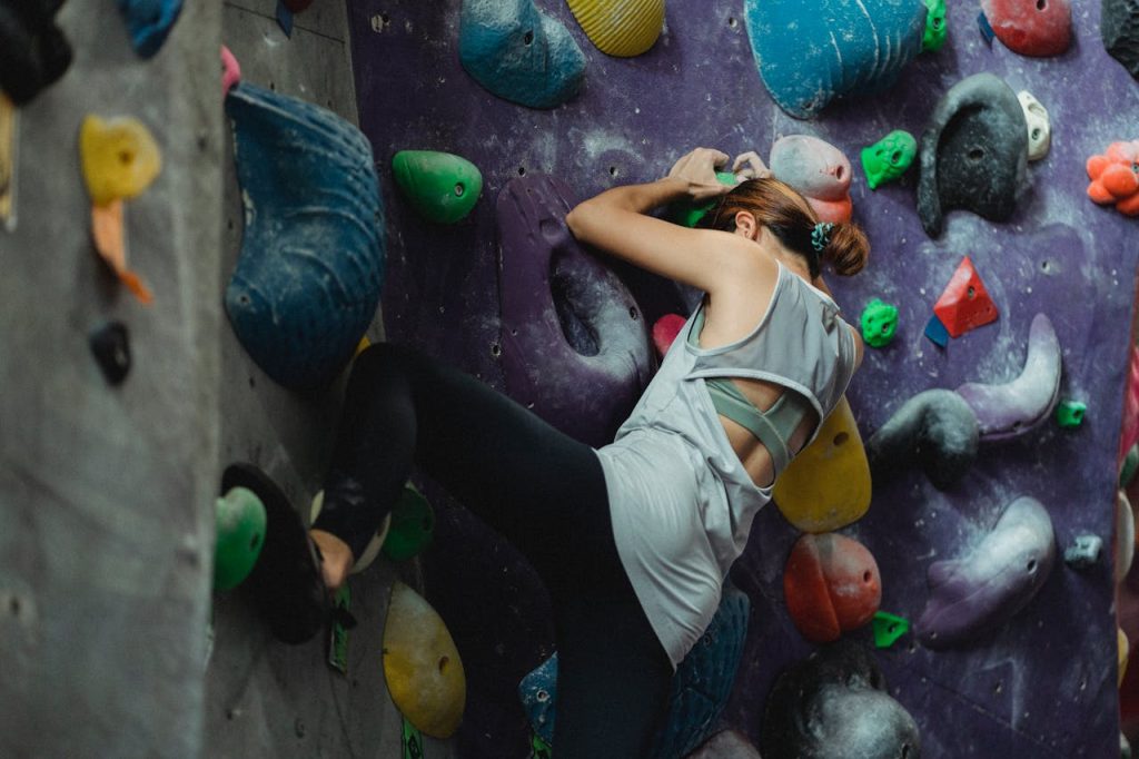 Back view of anonymous female athlete practicing extreme bouldering training for improving climbing skills