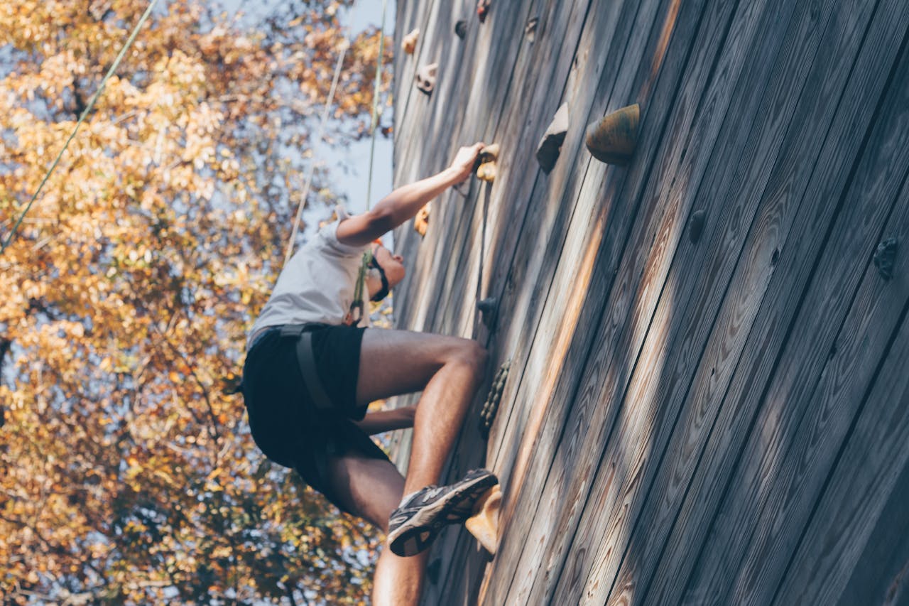 A person enjoying a thrilling wall climbing experience outdoors with fall foliage.